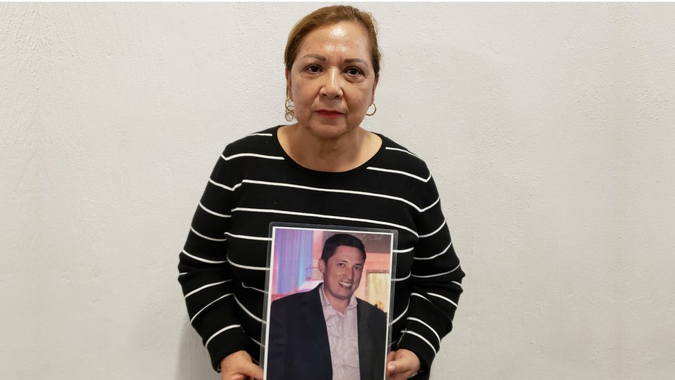 Guadalupe Aguilar holds up a framed photograph of her missing son
