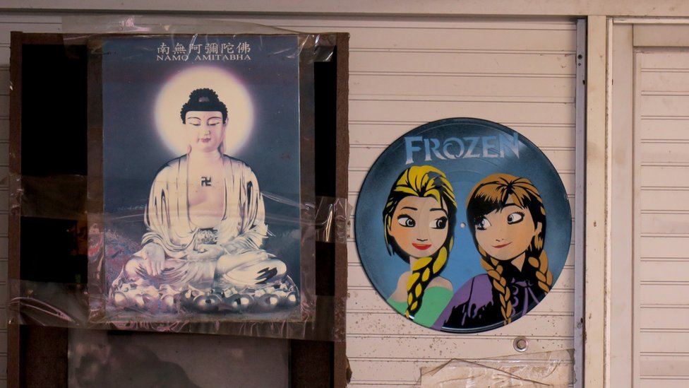郭卓堅辦公室內掛於牆上的觀音菩薩像（左）與畫上迪士尼卡通人物的舊黑膠唱片（右）