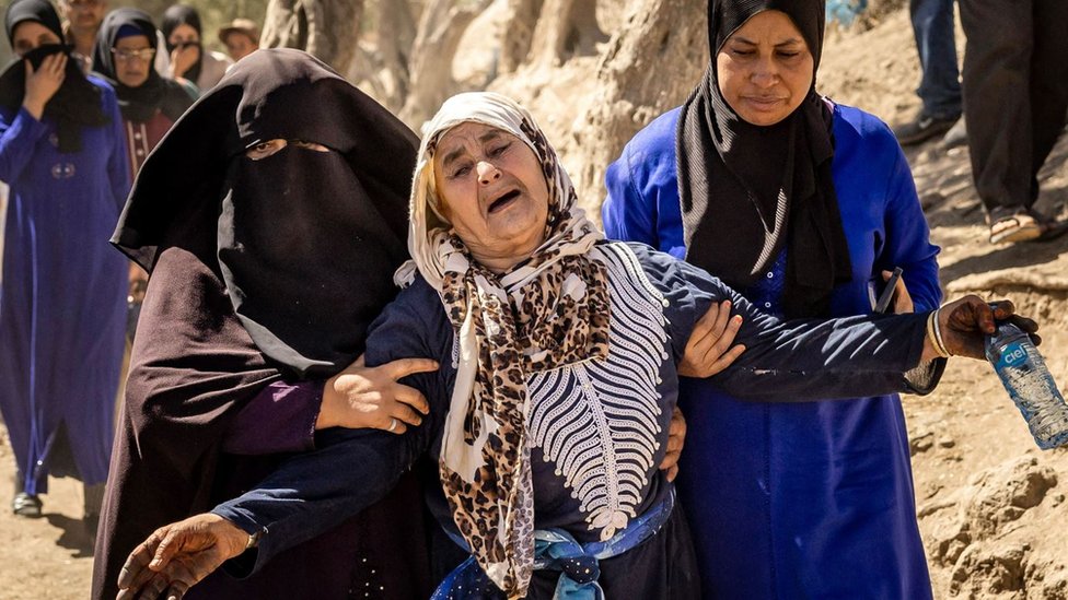 A woman is helped as she reacts to the death of relatives to the south-west of Marrakesh