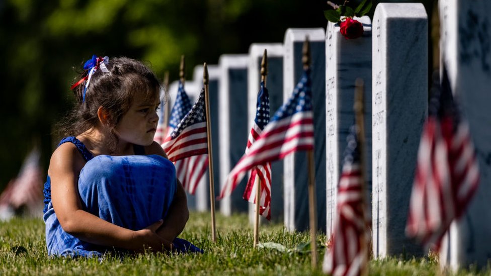 Una niña sentada en la hierba entre las lápidas de los muertos en las guerras de Irak y Afganistán, foto tomada el 31 de mayo de 2021 en Arlington, Virginia.