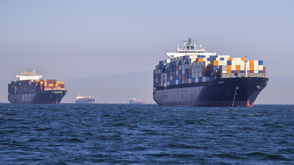 Dos buques repletos de contenedores, y dos más en el fondo, frente al puerto de Los Ángeles.