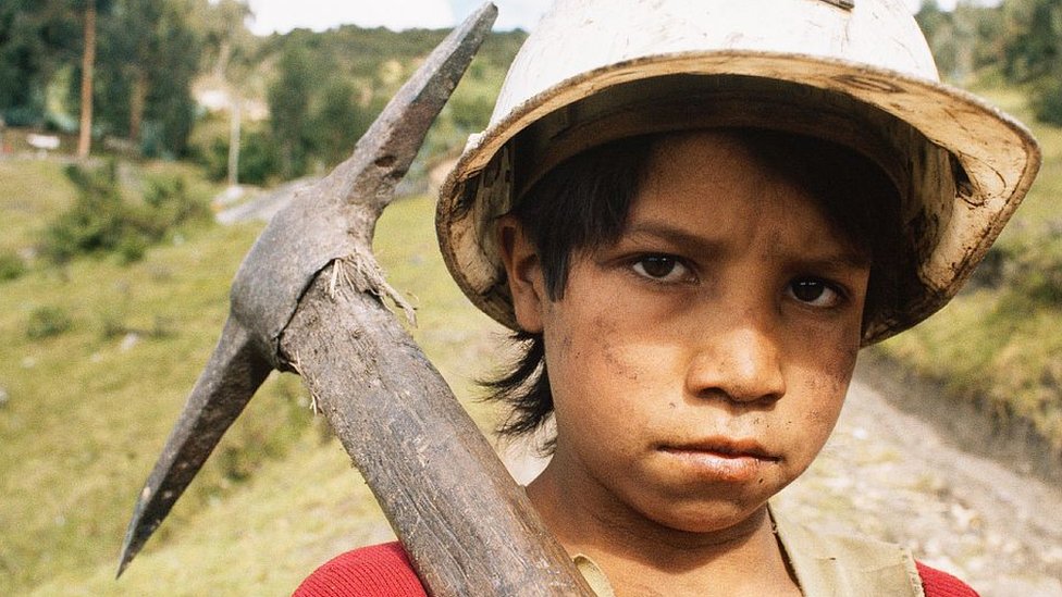 Niño trabajador con un pico para trabajar en una mina