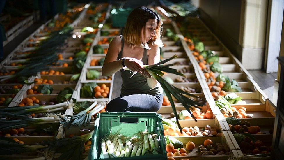 Chica preparando cajas de fruta.