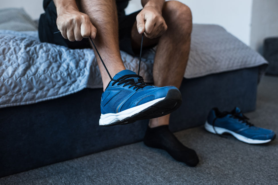 Un hombre se calza zapatillas para correr