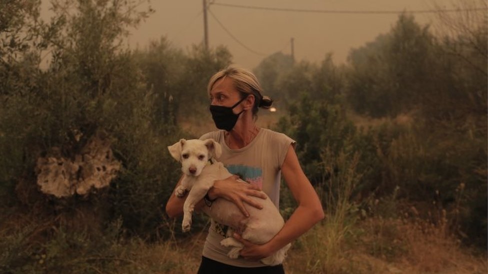 A local resident holds her dog that was rescued by locals during a wildfire