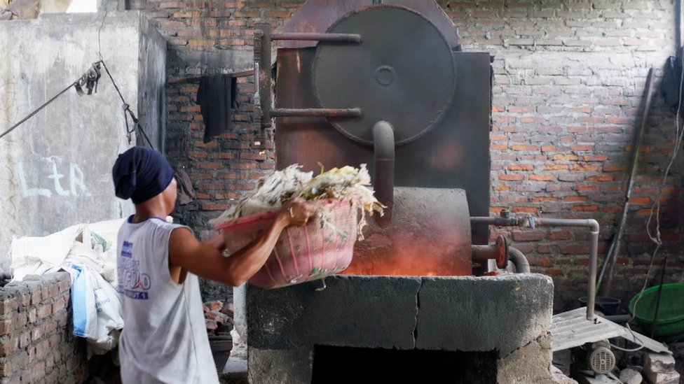 Un hombre coloca un fardo de plástico en un incinerador