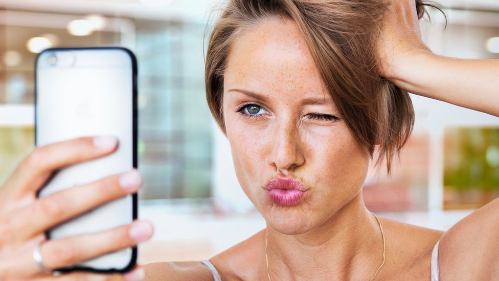 Una chica tomándose un selfie con el celular