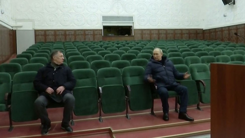 Russia's President Vladimir Putin (R) speaks with Deputy Prime Minister Marat Khusnullin while they sit in The Mariupol Philarmonic Theatre