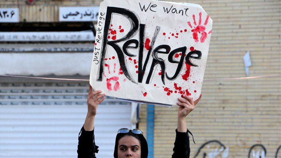 Иранский скорбящий в похоронной процессии держит плакат с надписью «Мы хотим отомстить»