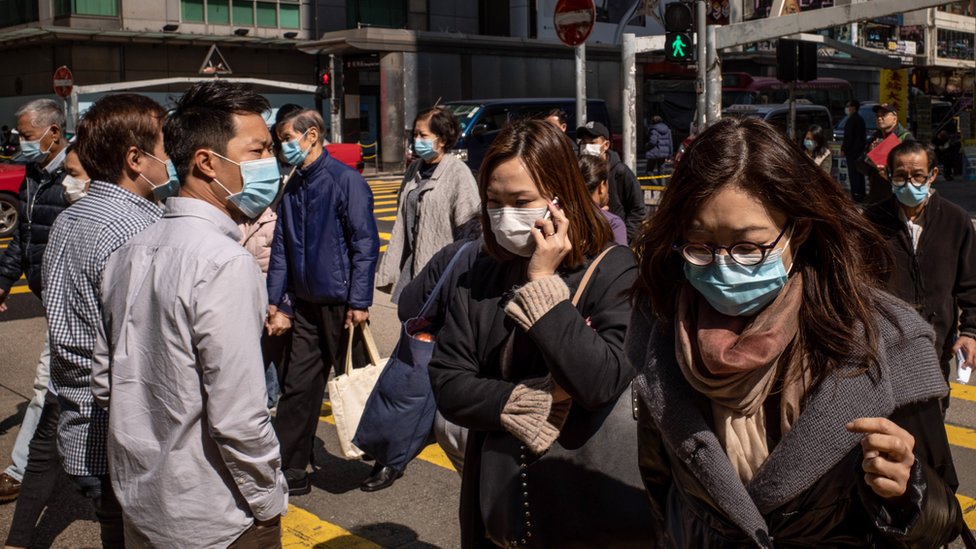 Residents wear surgical mask as they cross a street in a shopping district