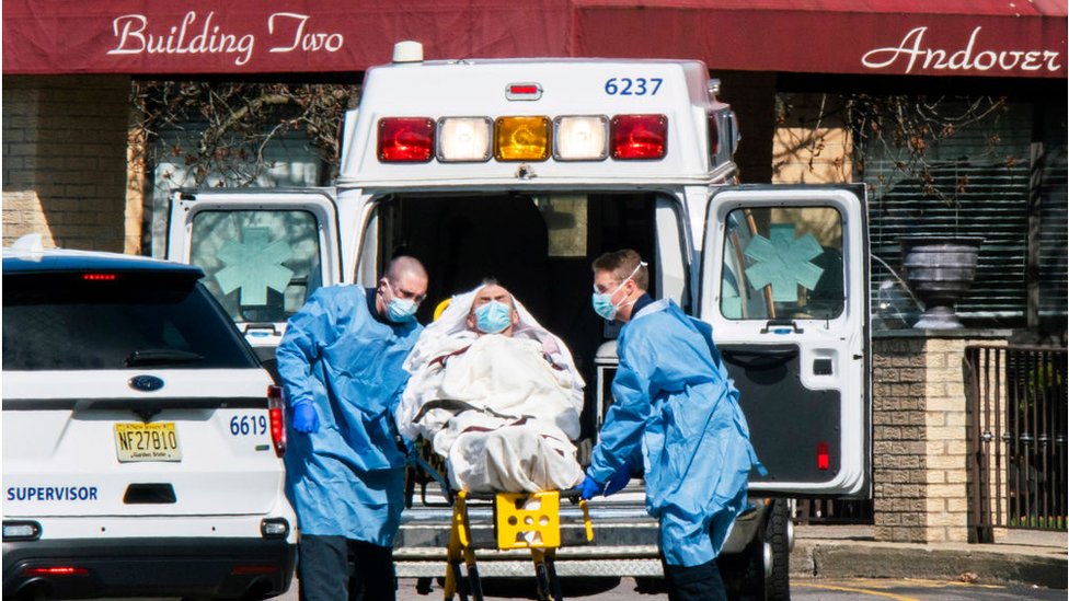 Медработники загружают пациента в машину скорой помощи