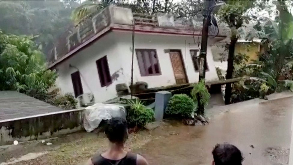 عدد من المواطنين الهنود يشاهدون منزلا ينجرف بفعل السيول