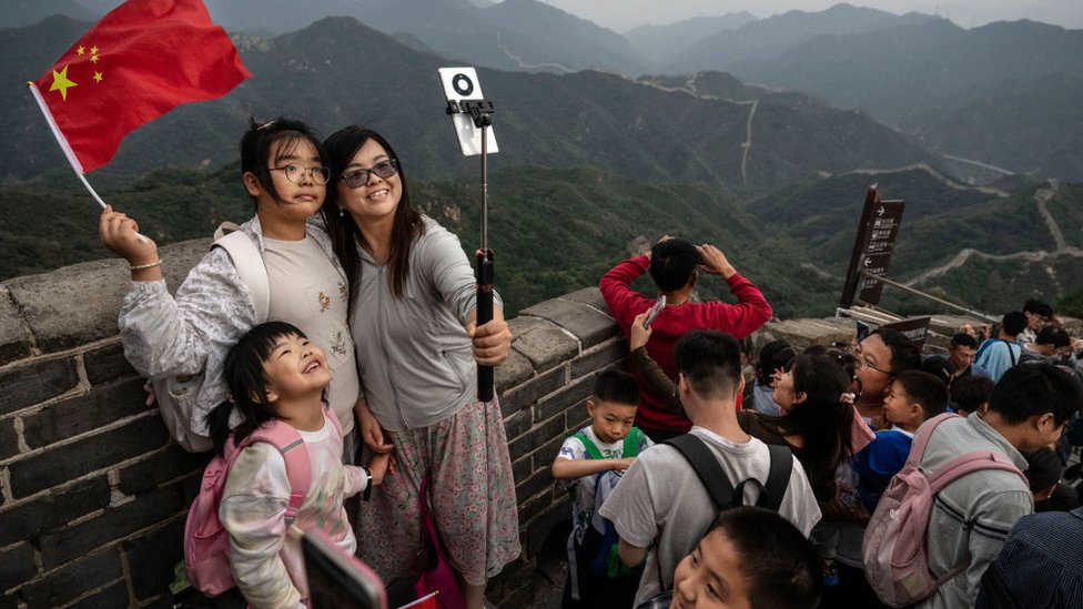 A family takes photos as they and others visit a section of the Great Wall during the National Golden Week holiday on October 2, 2023 in Beijing,