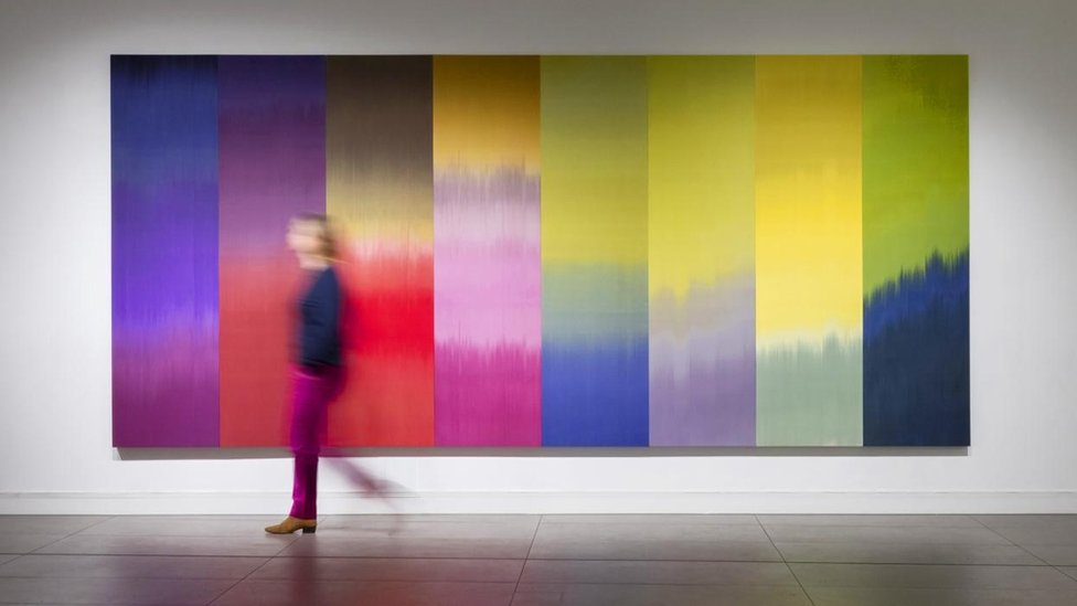 Una mujer frente a un muro colorido