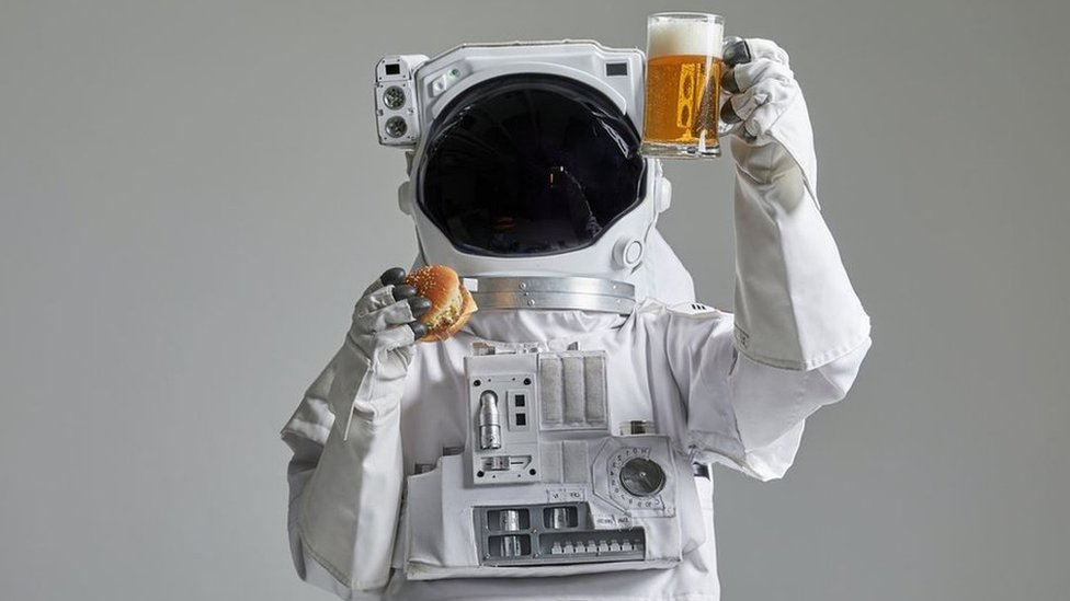 رائد فضاء مع كوب من البيرة والهامبرغر