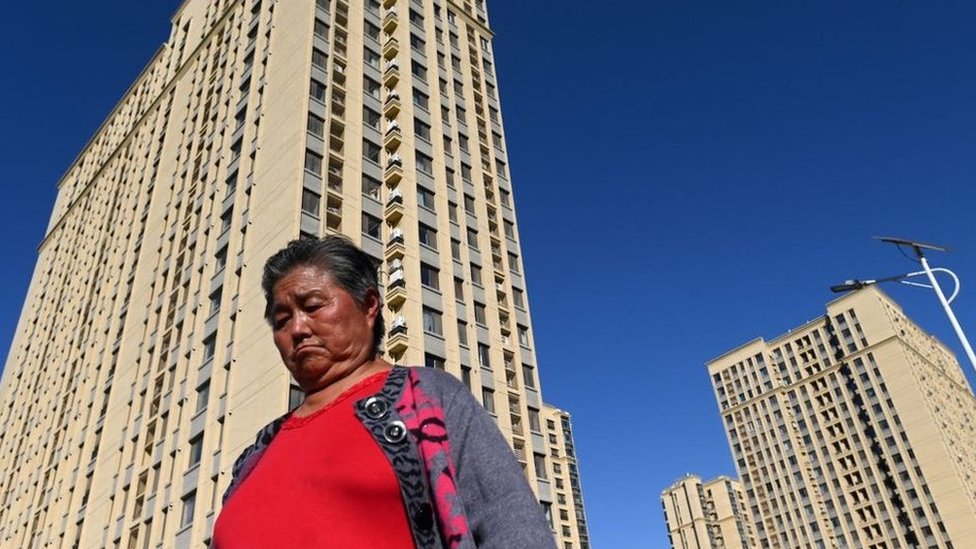 Una mujer pasa junto a unos rascacielos en Pekín