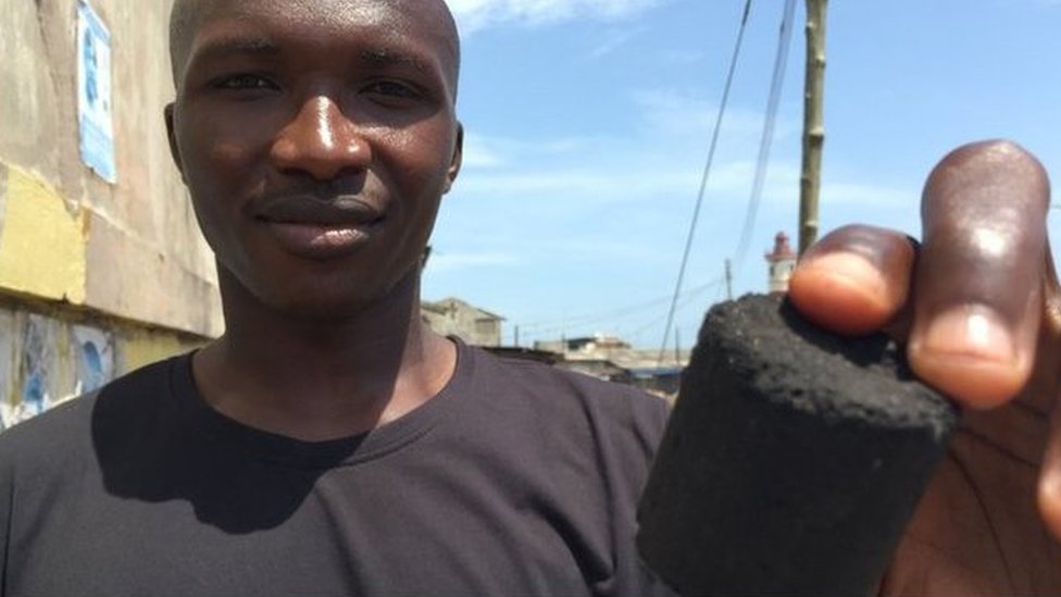 Ghana's Sampson Sayibu shows off a charcoal shape made from recycled human toilet waste