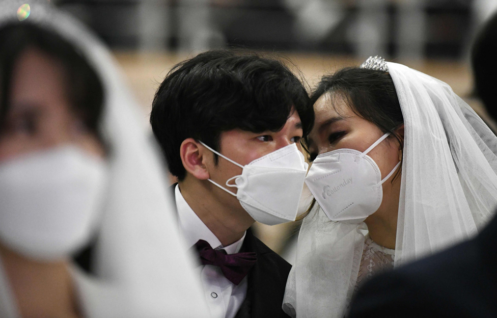 لحظة خاصة بين زوجين يرتديان قناعين خلال حفل زفاف جماعي نظمته كنيسة التوحيد في غابيونغ