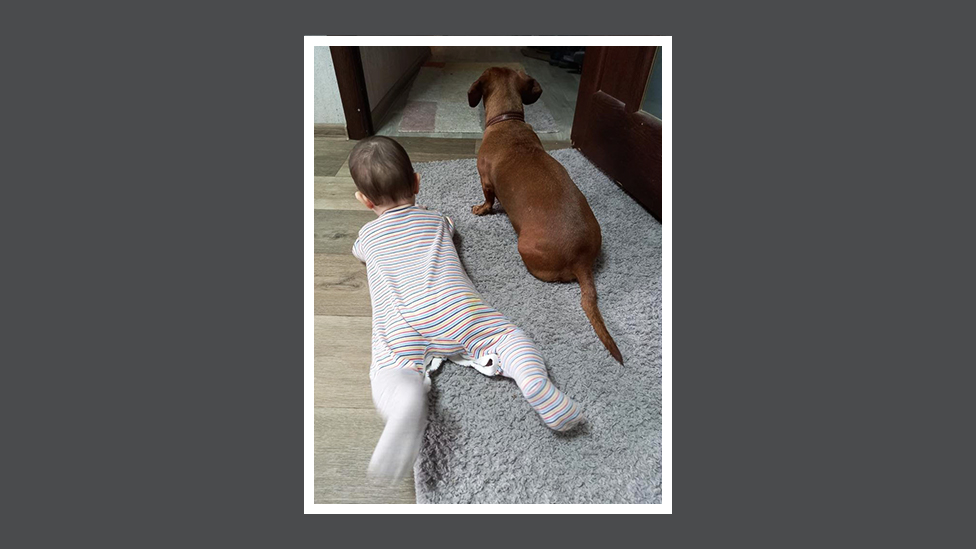 O bebê e o cachorro de Ievegen estão deitados no chão em sua casa em Dnipro