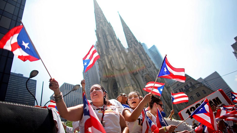 Casi 450.000 puertorriqueños han migrado a EE.UU. en la última década. Comunidad puertorriqueña en EE.UU. celebrando con banderas de la isla.