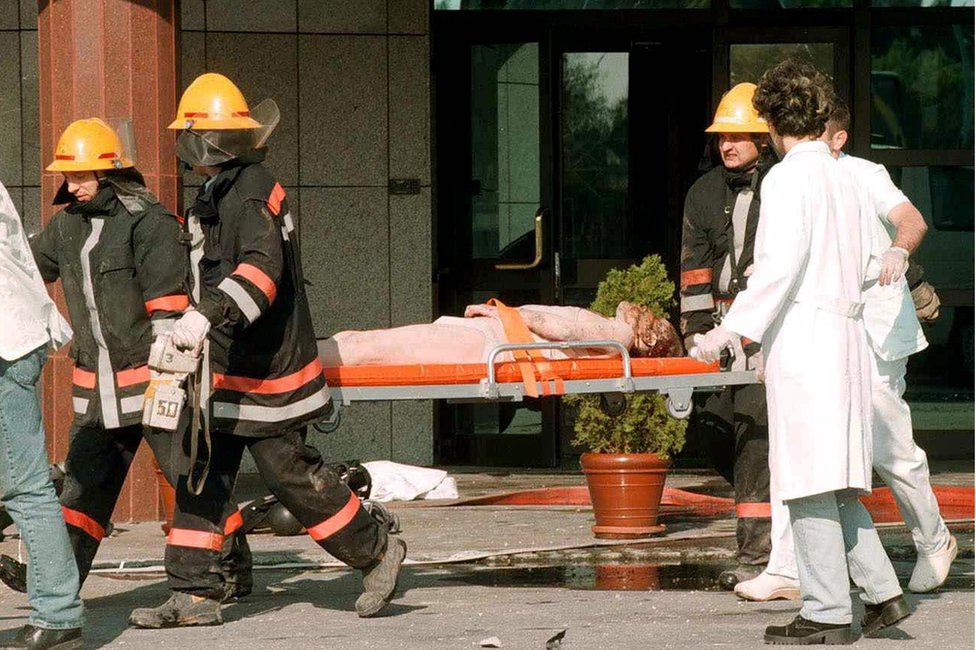 Неизвестные раненые сотрудники китайского посольства уносятся на носилках югославскими спасателями после пожара в китайском посольстве рано в субботу, 8 мая 1999 г.,