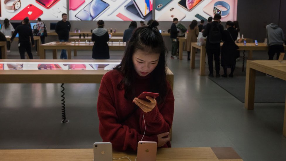 Una joven china mira un iPhone en una tienda de Apple en la ciudad sureña de Shenzhen.