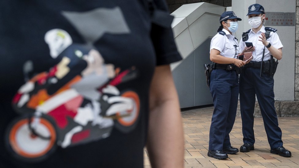 香港高等法院外兩名警員站在一名身穿摩托車手造型汗衫的聲援者背後（27/7/2021）