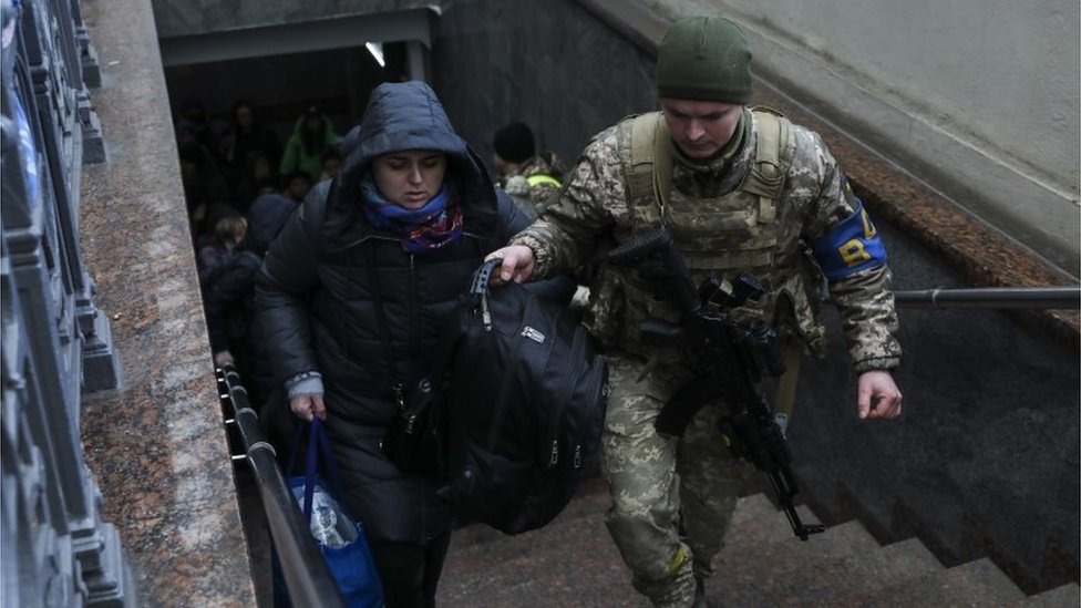 Un soldado ucraniano ayuda a una mujer en la estación de tren de Lviv, al oeste de Ucrania.
