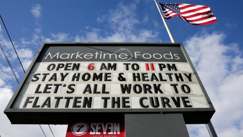 Ярлык на рынке в Сиэтле, штат Вашингтон, гласит: «Оставайтесь дома и здоровы, давайте все будем работать, чтобы сгладить кривую» |
