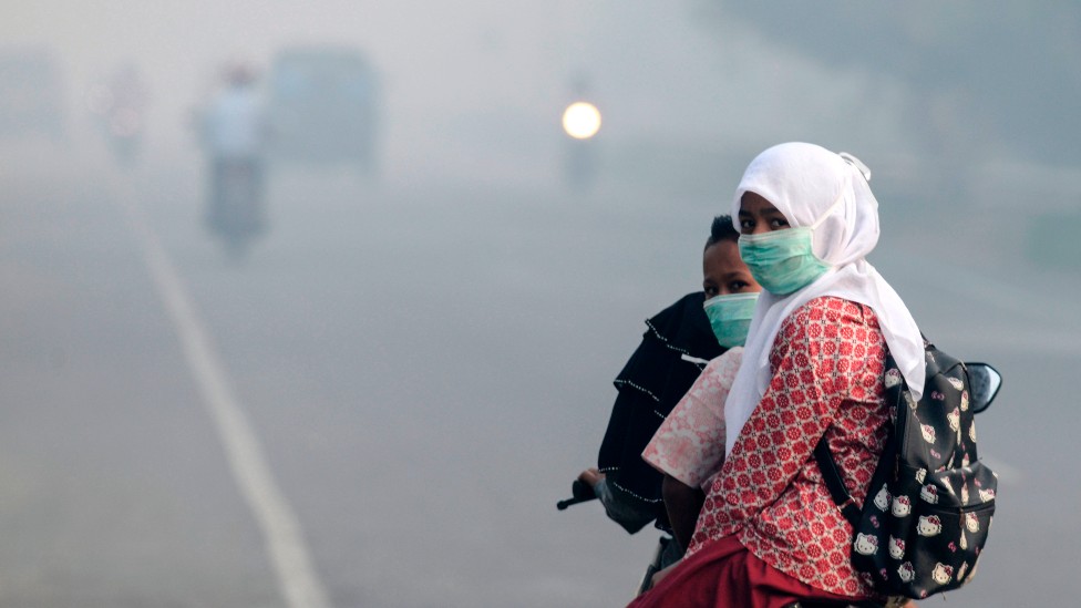 Mujeres en Indonesia con mascarilla por el humo de incendios de turba