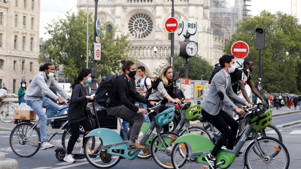 Pengendara sepeda yang mengenakan masker melintas di depan Katedral Notre Dame.