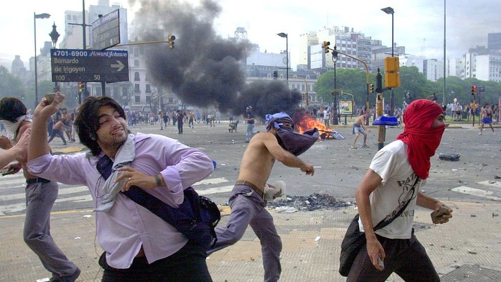Протестующие бросают камни в полицию в разгар экономического кризиса в Аргентине 20 декабря 2001 г.