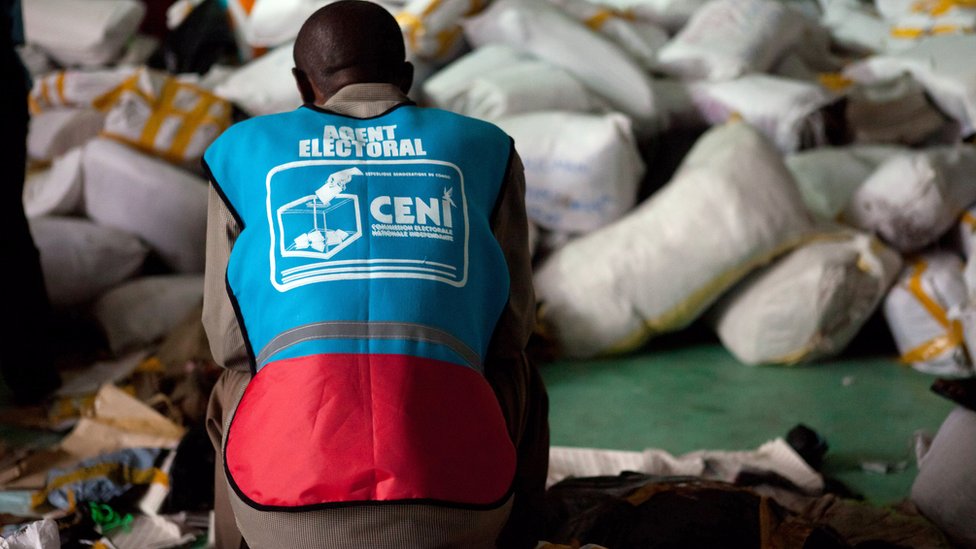 Избирательный агент Национальной независимой избирательной комиссии (CENI) сидит на сумке с бюллетенями на складе в Киншасе 3 декабря 2011 г.