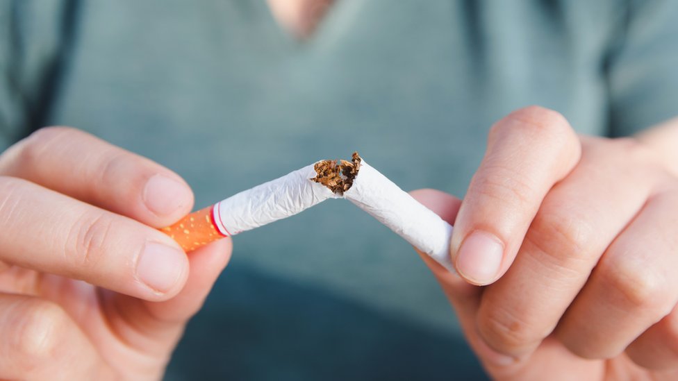 Una mujer parte un cigarrillo.