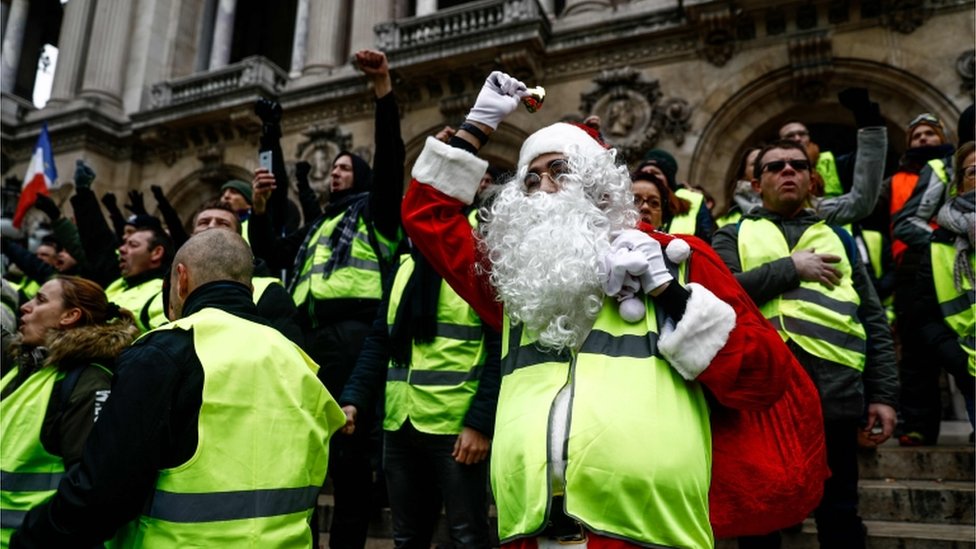 A protester dressed as Santa Claus and wearing a yellow vest (gilet jaune) demonstrates on the stairs of the Opera Garnier in Paris, on December 15, 2018