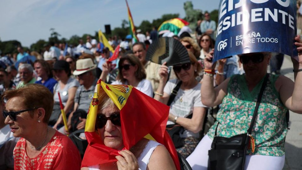 Supporters of People's Party (PP) shelter from the heat during a rally with opposition leader Alberto Nunez Feijoo at Retiro park ahead of elections in Madrid, Spain, June 18, 2023.