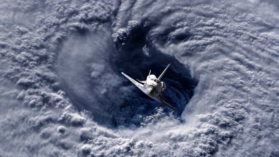 Un transbordador espacial volando sobre un huracán en la Tierra