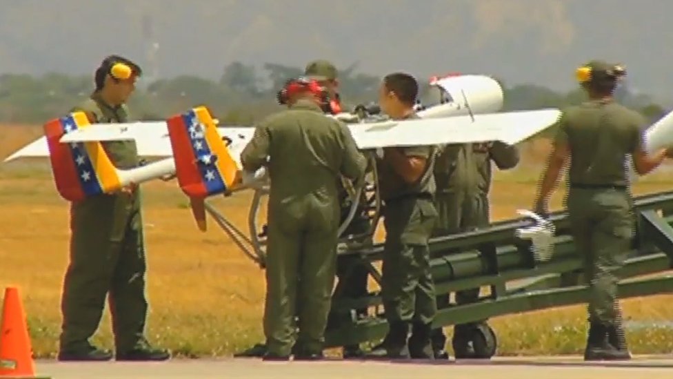 Homens fardados mexendo em drone em pista aérea