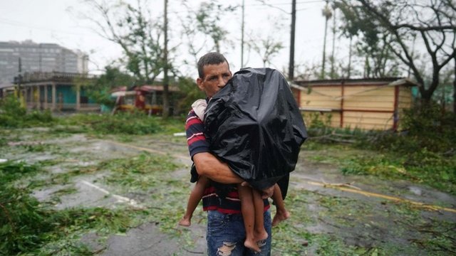 Pai carrega seus filhos em meio a forte chuva