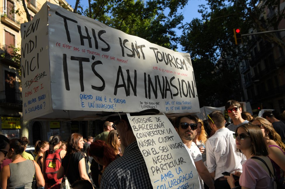Barcelona'da geçen yıl düzenlenen eylemlerde bir genç, 'Bu turizm değil, bir istila' pankartı taşımıştı.