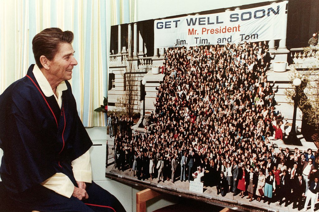 El presidente Ronald Reagan ve una gigantesca tarjeta de bienvenida mientras se recupera en el Hospital George Washington de una herida de bala sufrida en un intento de asesinato por parte de John Hinckley, Jr.