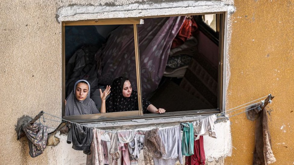 Women look through broken windows in the Gaza Strip following Israel's attacks.