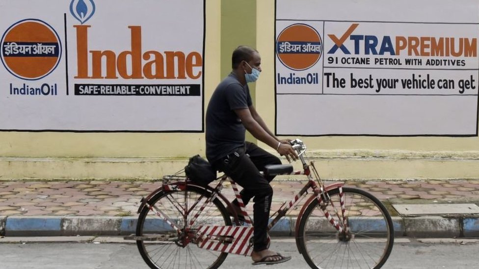 Man on a bicycle passes by a petrol station in Kolkata as oil prices rise