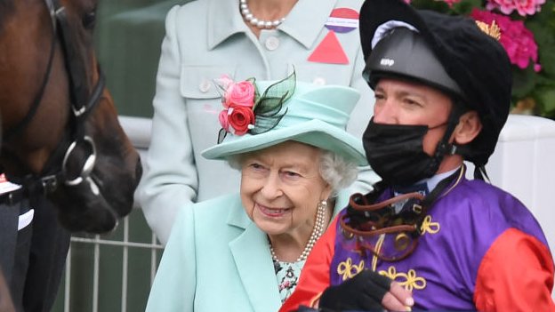 A rainha sorrindo ao lado do jóquei Frankie Dettori