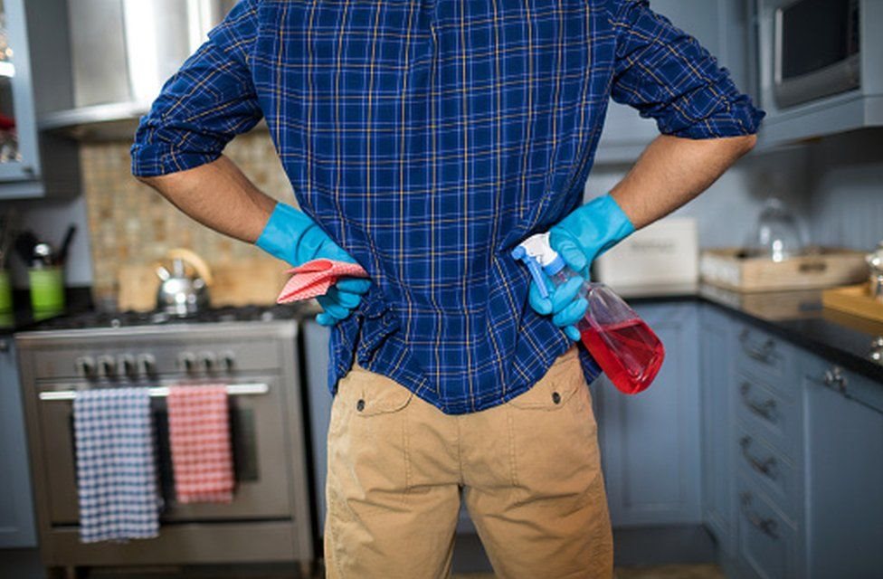 رجل في مطبخ يمسك أدوات تنظيف