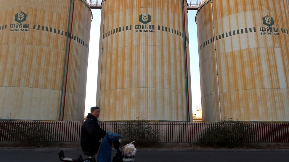 A man cycles past storage facilities of China's state grain stockpiler Sinograin near Tianjin port, China December 12, 2019