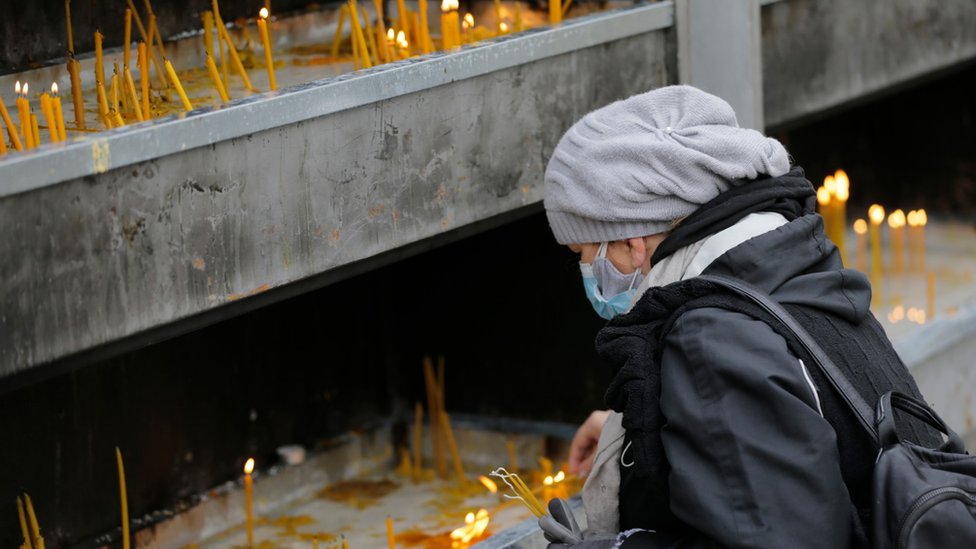 Православный верующий зажигает свечу покойному сербскому патриарху Иринею в Белграде, Сербия, 21 ноября 2020 года.