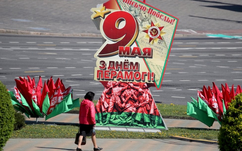 A woman walks past a patriotic placard as Minsk prepares to celebrate Victory Day, 7 May 2020