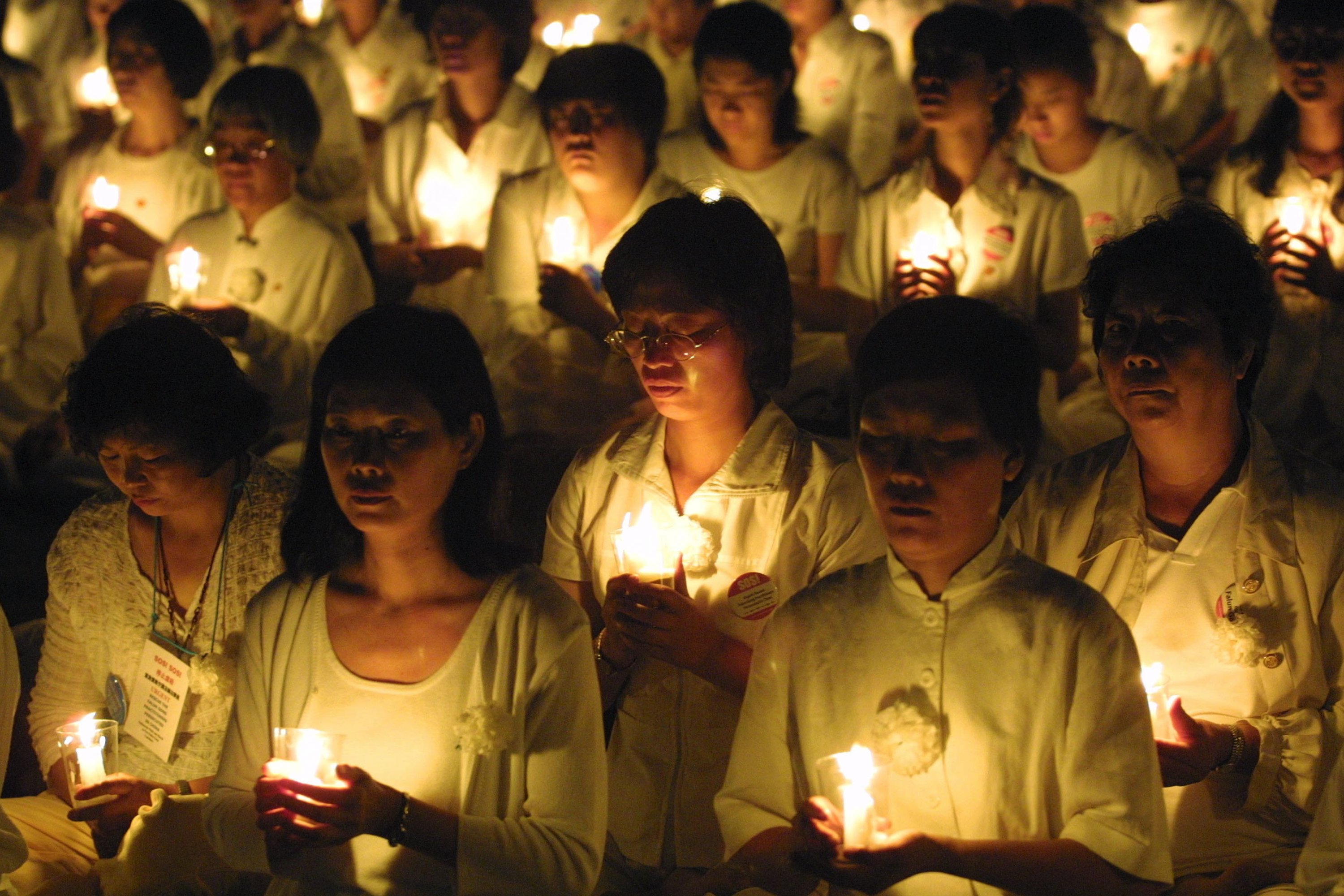 Members of the Falun Gong spiritual movement hold candles during a candlelight vigil July 19, 2001 in Washington, DC
