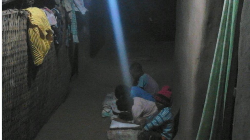 Деревенские дети учатся при электрическом освещении